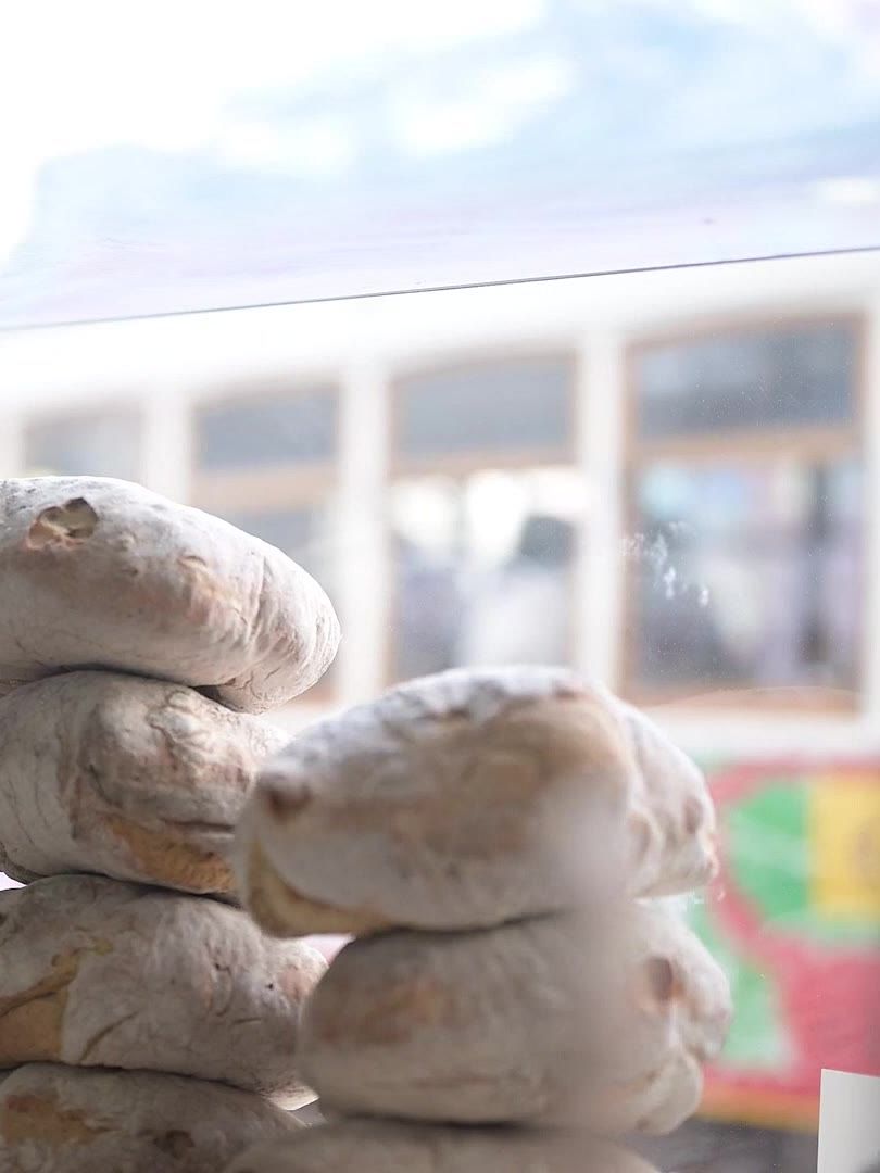 Pão empilhado ao balcão da Tropical da Graça, com o elétrico a passar lá fora